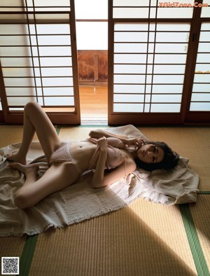 A woman laying on a bed in a pink lingerie.