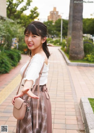 A woman in a red shirt and blue and white polka dot skirt.