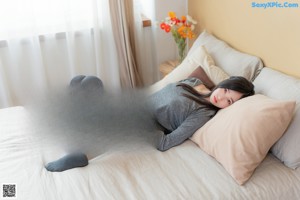 A woman sitting on a bed holding a cell phone.