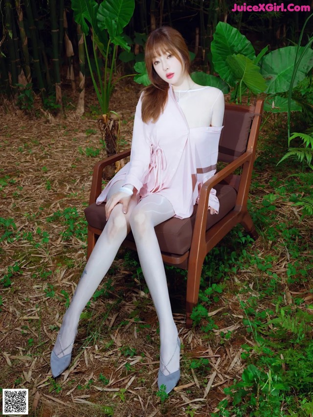 A woman sitting on a chair in the woods.