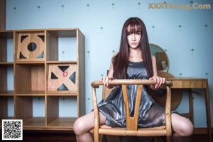 A woman in a silver dress sitting on a chair.