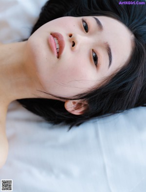 A naked asian woman with a hand on her chin.