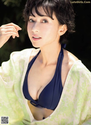 A woman in a blue top and yellow skirt posing by a pool.