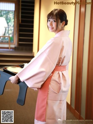 A woman in a pink kimono poses for a picture.