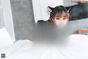 A woman in a black lingerie laying on a bed.
