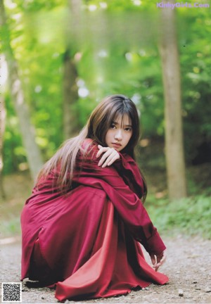 A young woman leaning against a fence with her hand on her chin.