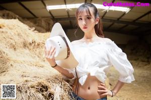 A woman laying on top of a pile of hay.