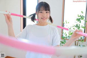 A young woman sitting on the floor with a hula hoop.