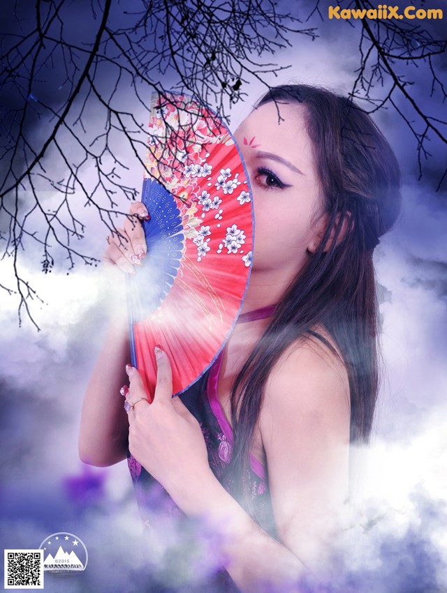 A woman holding a red and blue fan in front of her face.