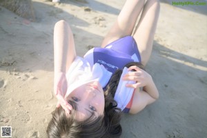 A woman in a bathing suit posing on the beach.