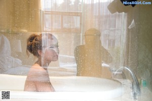 A naked woman sitting in a bathtub in a bathroom.