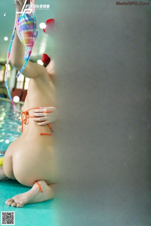 A woman in a bikini playing with balls in a pool.