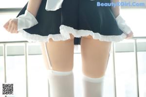 A woman in white stockings and black high heels sitting on a counter.
