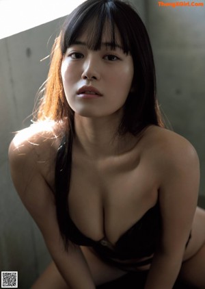 A woman in a white lingerie sitting on a bed.