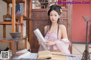 A woman in a pink dress holding a fan.