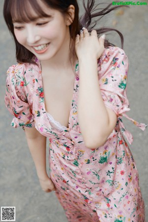 A woman in a pink floral dress is walking down the street.