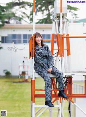 A woman in a blue uniform standing in front of an airplane.