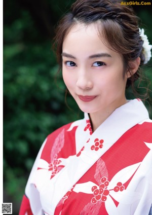 A woman in a red and white kimono leaning against a wall.