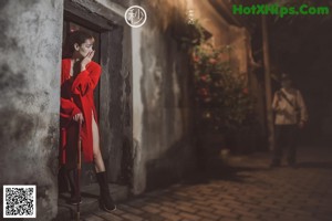 A woman in a red kimono leaning against a wall.