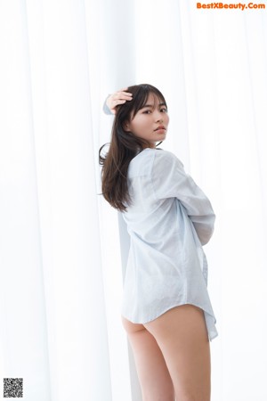 A woman standing in front of a white curtain.