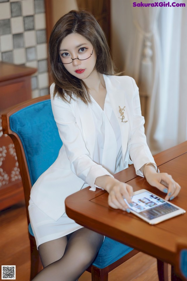 A woman sitting at a table with a tablet computer.