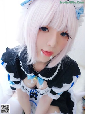 A woman in a blue and white outfit is sitting on a bed.