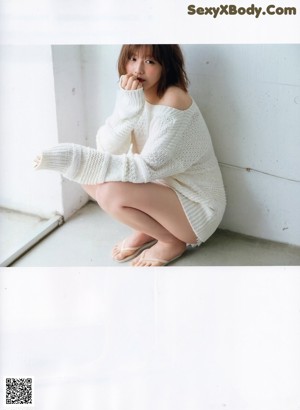 A woman in a white sweater sitting on the floor.