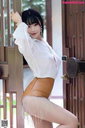 A woman in a white shirt is posing for the camera.