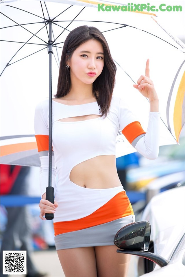 A woman in a white and orange dress holding an umbrella.