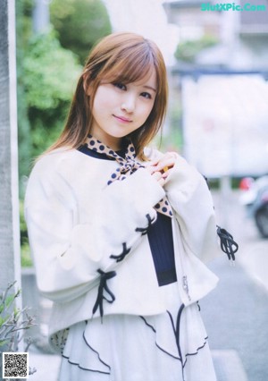 A woman wearing a white jacket and a polka dot scarf.
