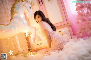 A woman in a white lingerie is posing in front of a Christmas tree.