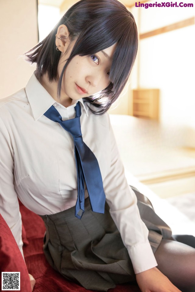 A woman in a school uniform sitting on a bed.