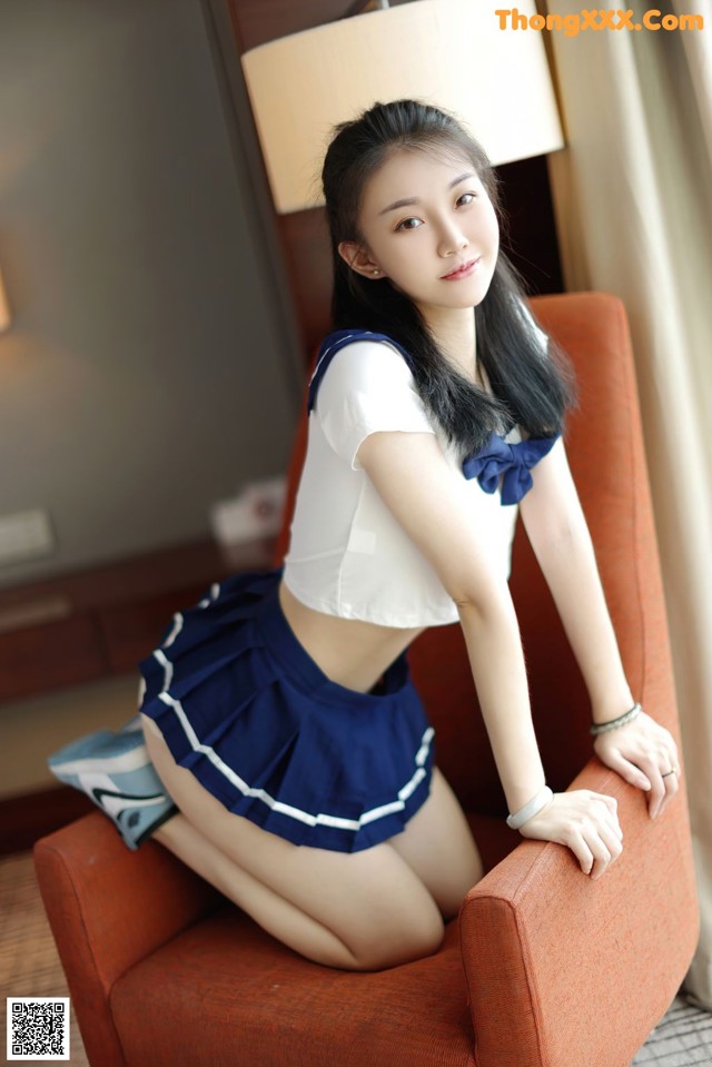 A woman in a sailor outfit sitting on a chair.