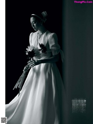 A woman in a wedding dress holding a bouquet of flowers.