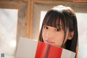 A young woman holding a book over her head.